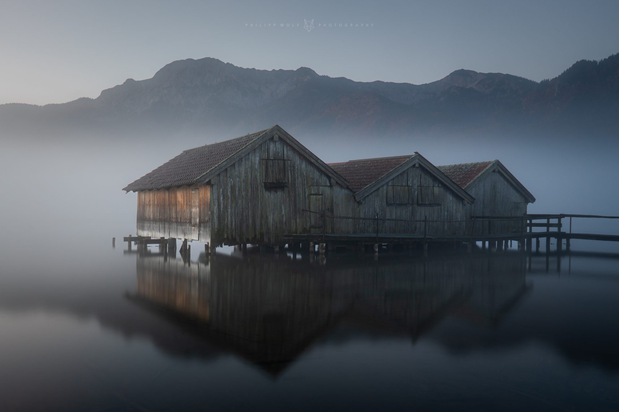 Bootshäuser im Morgennebel an einem bayerischen See