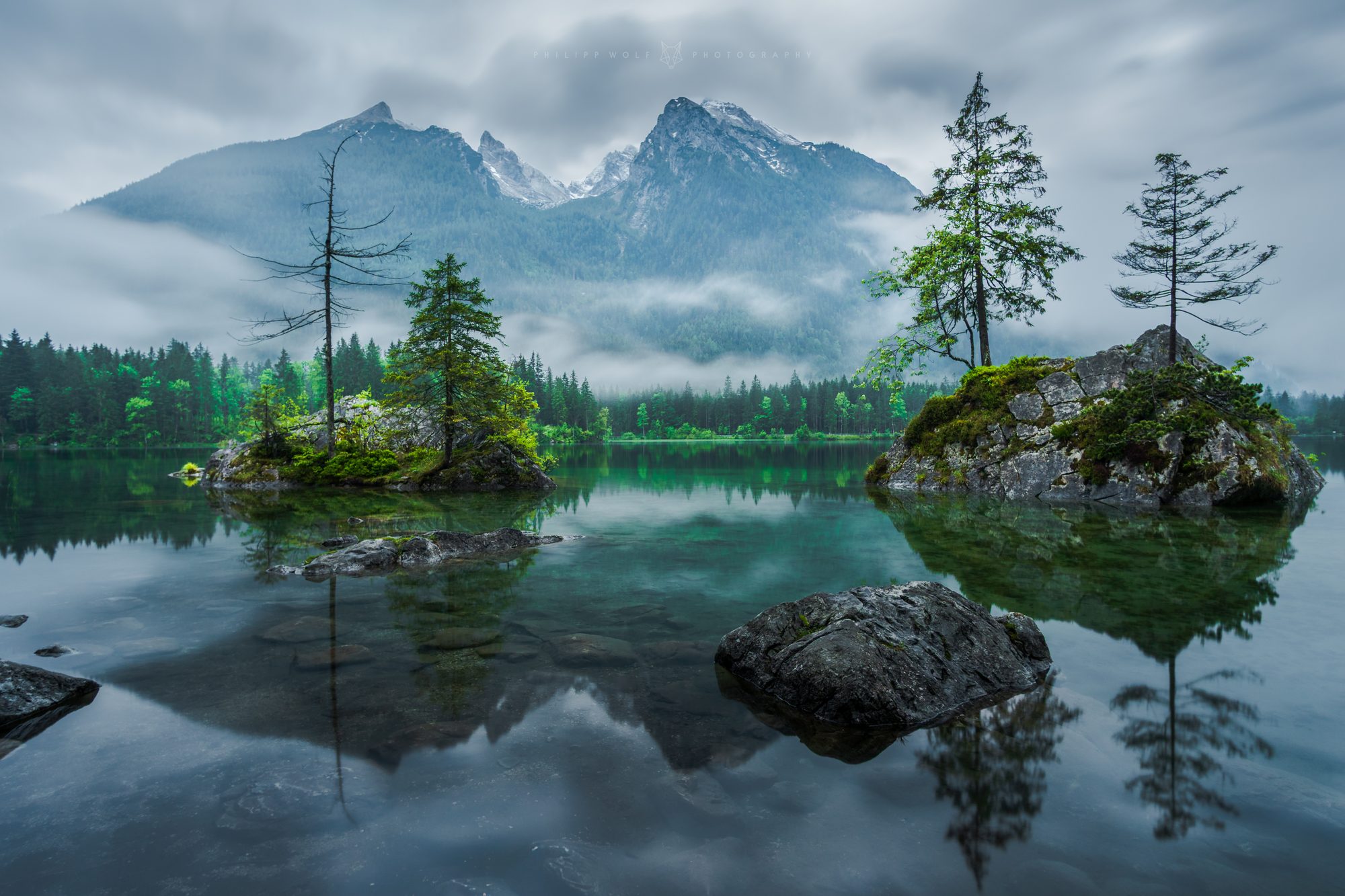 Nebelverhangene Felsinseln im Hintersee vor dem Berchtesgadener Bergpanorama