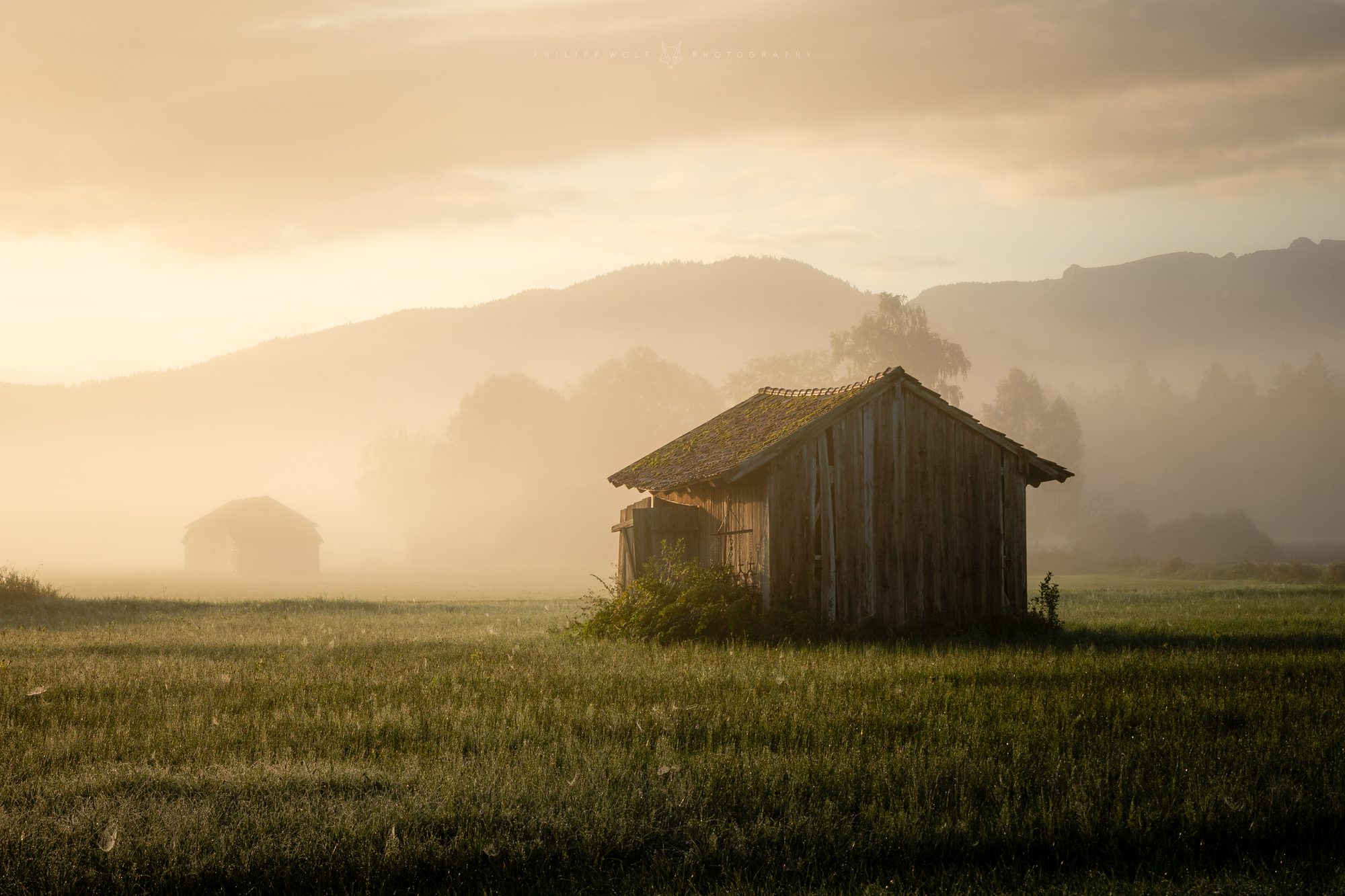 Alte Holzscheunen im goldenen Morgennebel, Bayern
