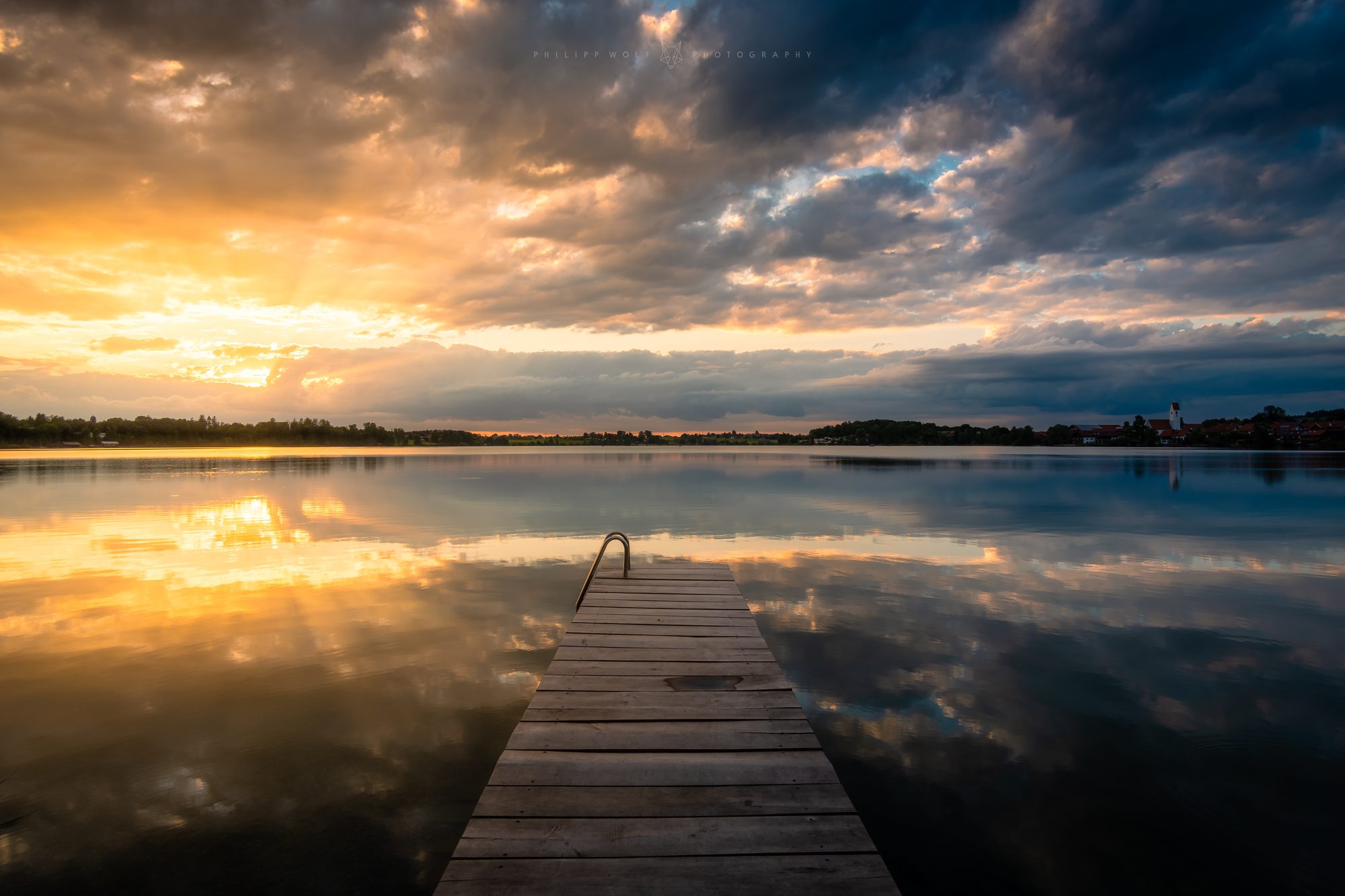 Bootssteg an einem bayerischen See bei dramatischem Sonnenuntergang