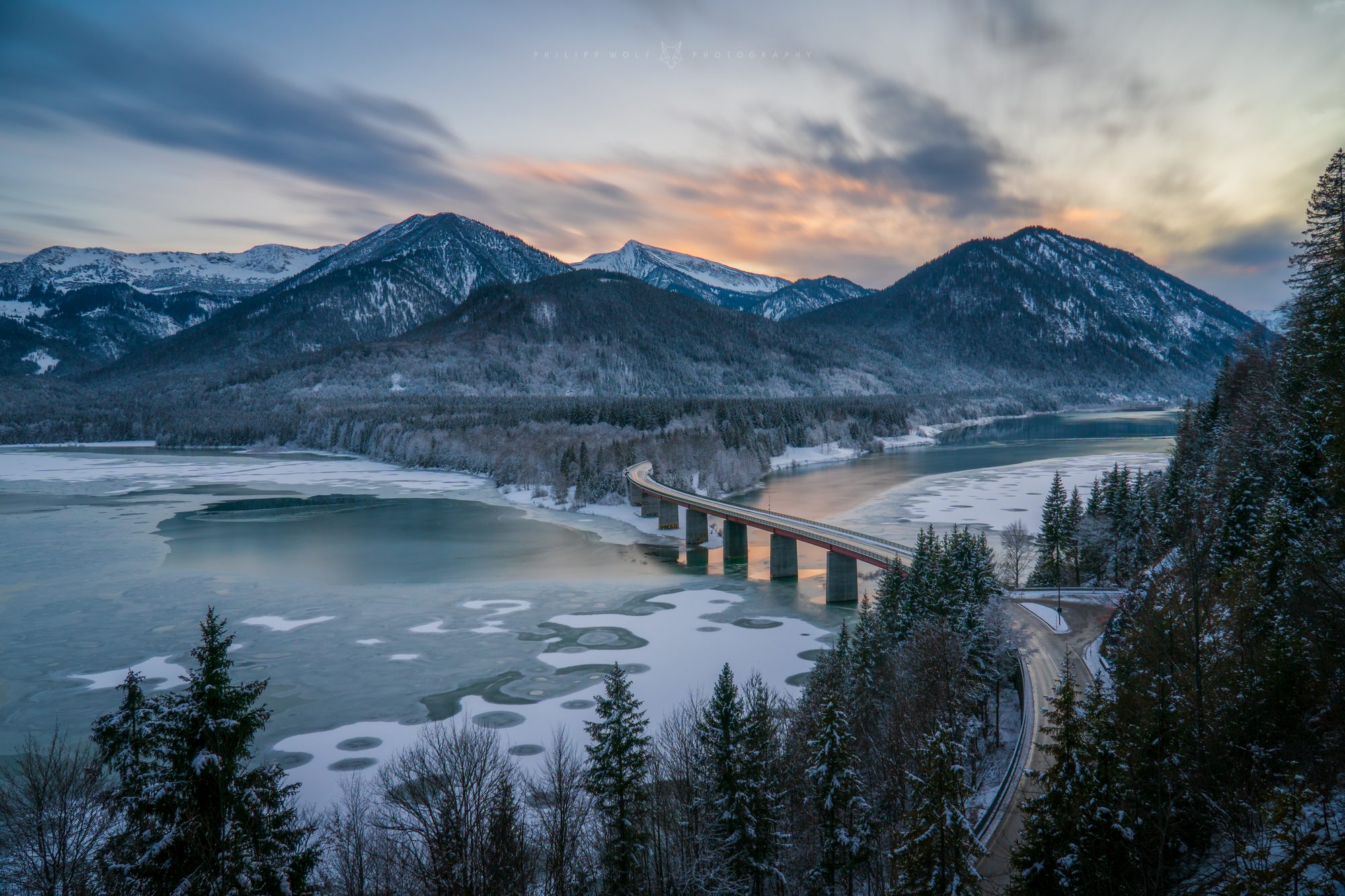 Brücke über den winterlichen Sylvensteinsee vor Bergpanorama